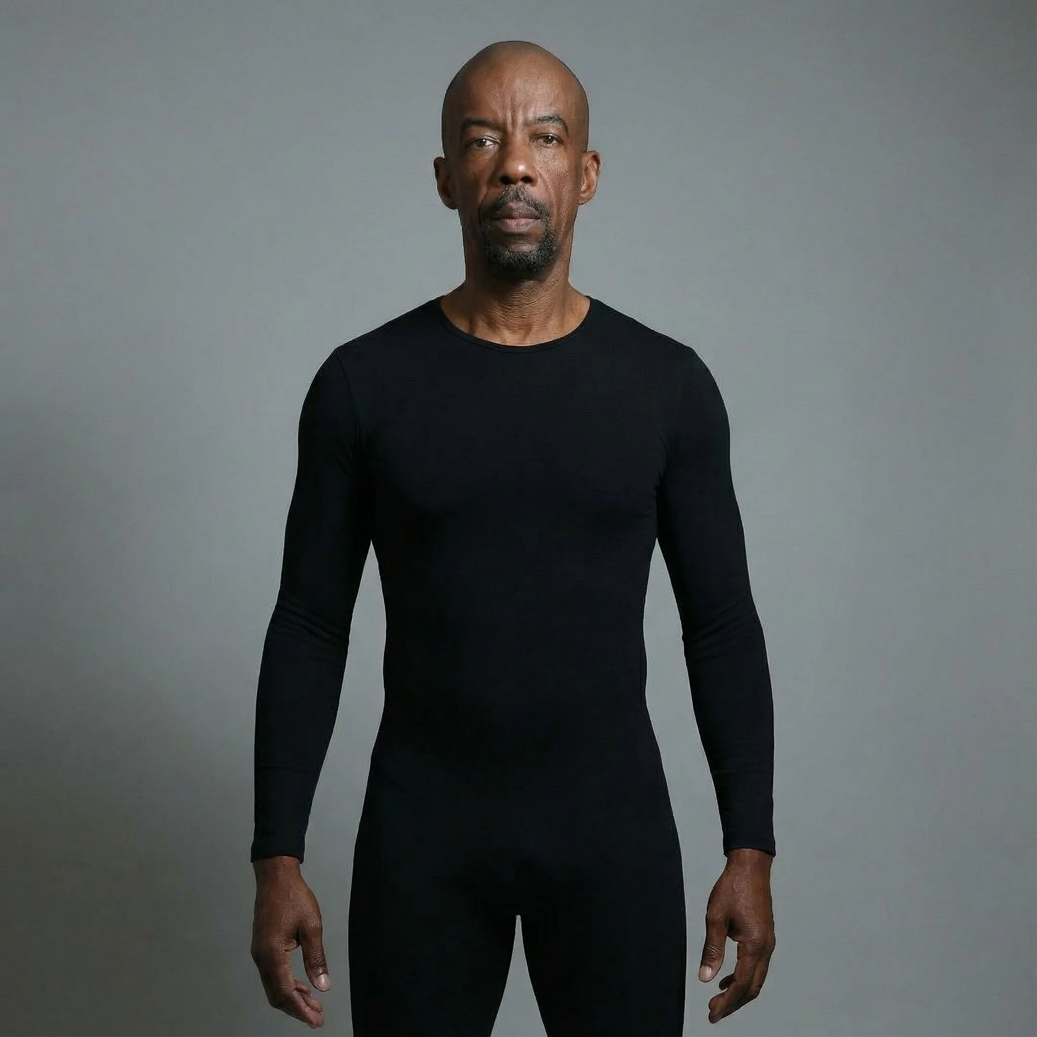 Photoreal digital twin of a man with brown hair in an all-black jacket and matching pants, hands relaxed by his sides against a cool gray studio wash.